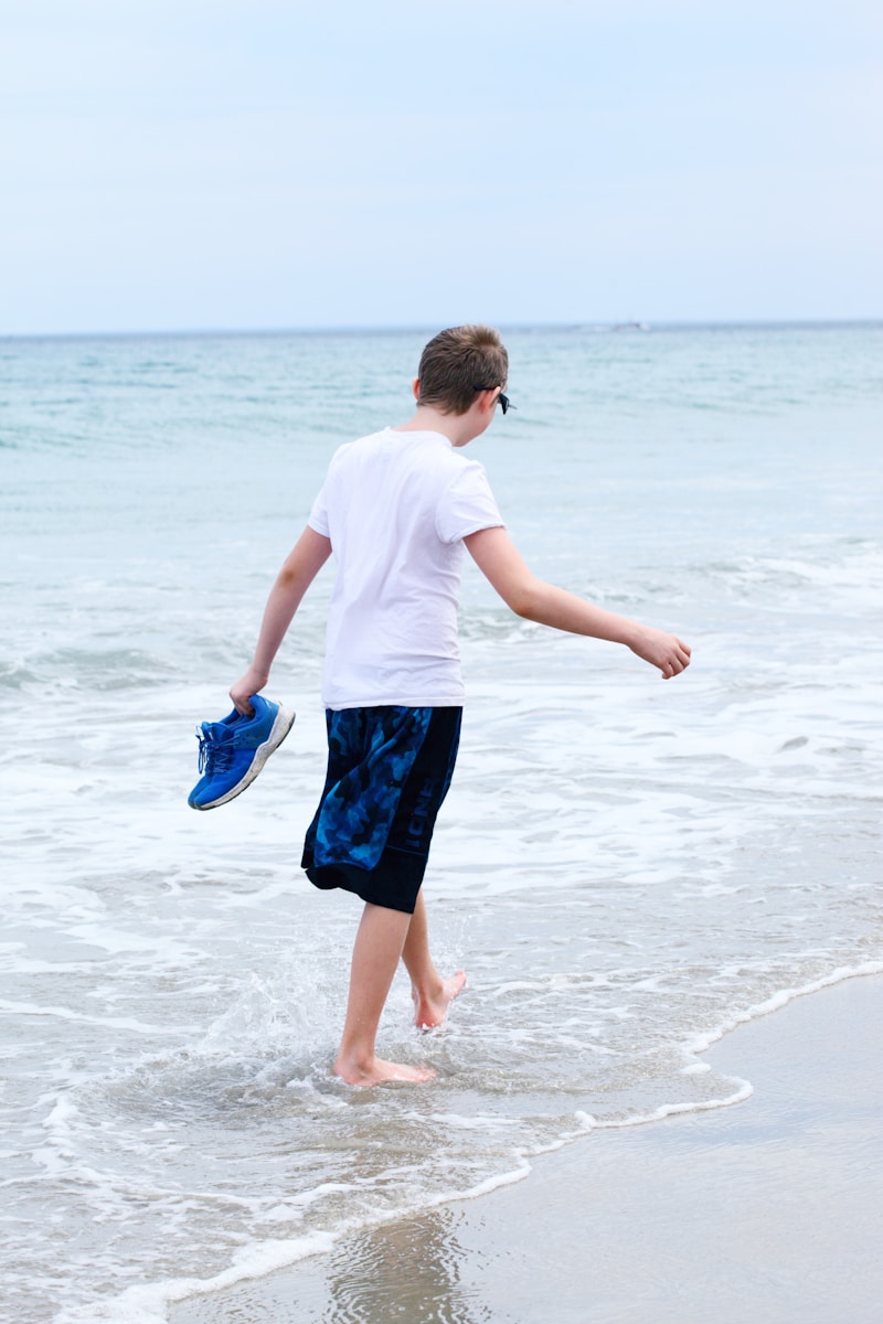 boy in white t-shirt and blue shorts running on beach during daytime because he had time to prepare your business before leaving for vacation